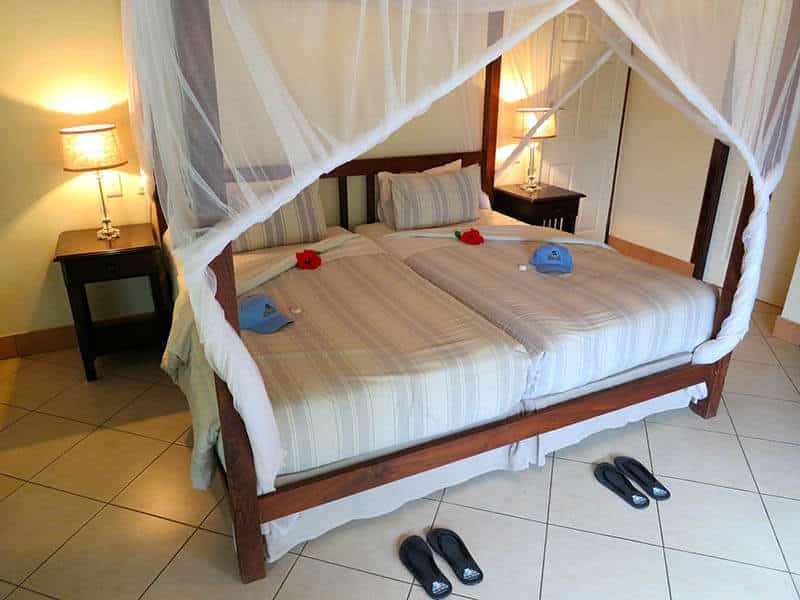 Double bed with complimentary hat and slippers for guests at Vila Do Paraiso