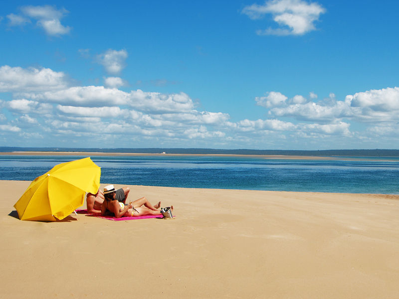 Couple sitting under a yellow umbrella on the beach