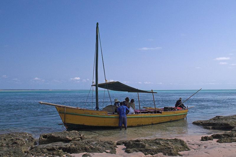 a dhow sitting off the coastline of the beach in Mozambique