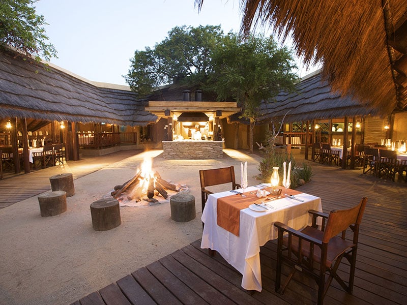 outside dining area with lit fire pit in the middle at Kapama River Lodge in Kruger National Park