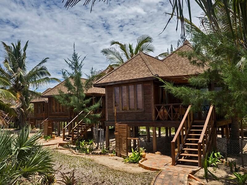 Three medium wooden bungalows with trees surrounding them at Sentidos Beach Retreat in Mozambique