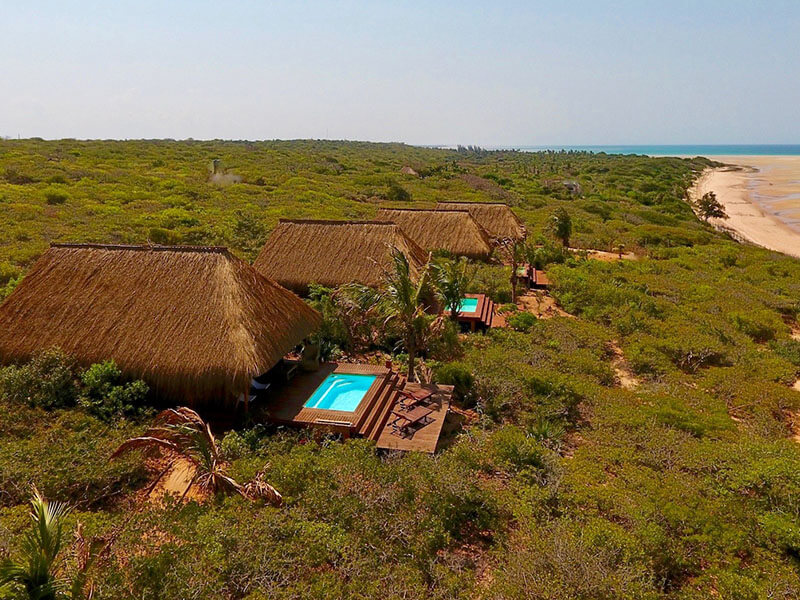 four small lodge buildings with private pools overlooking the ocean with bush surrounding them in Mozambique