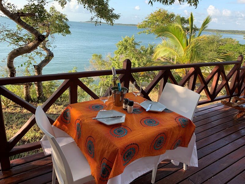 Table and chairs set up with cutlery and a bottle of sparkling water overlooking the ocean at Moyeni Lodge in Mozambique