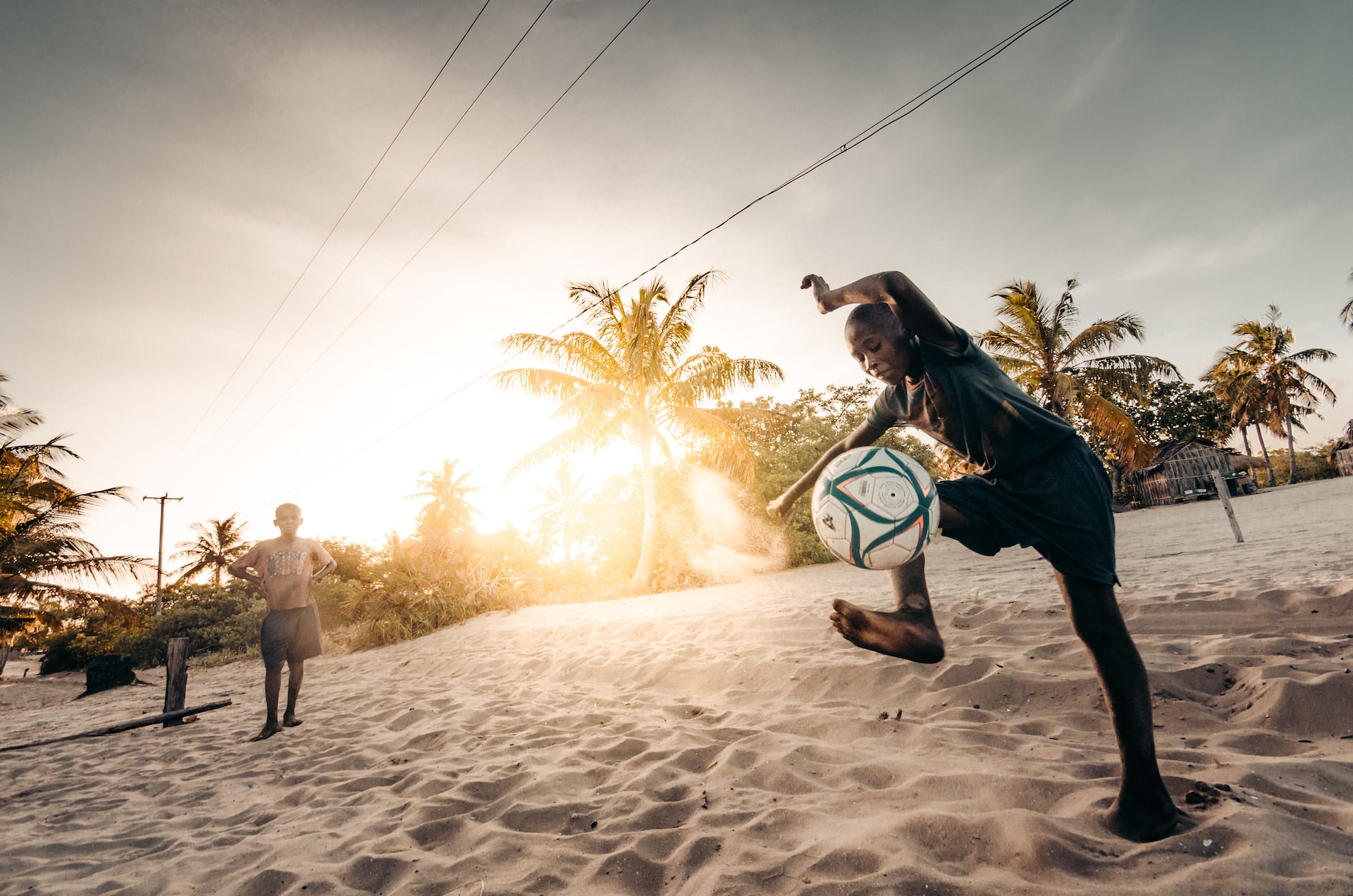 A local boy playing soccer on the beach