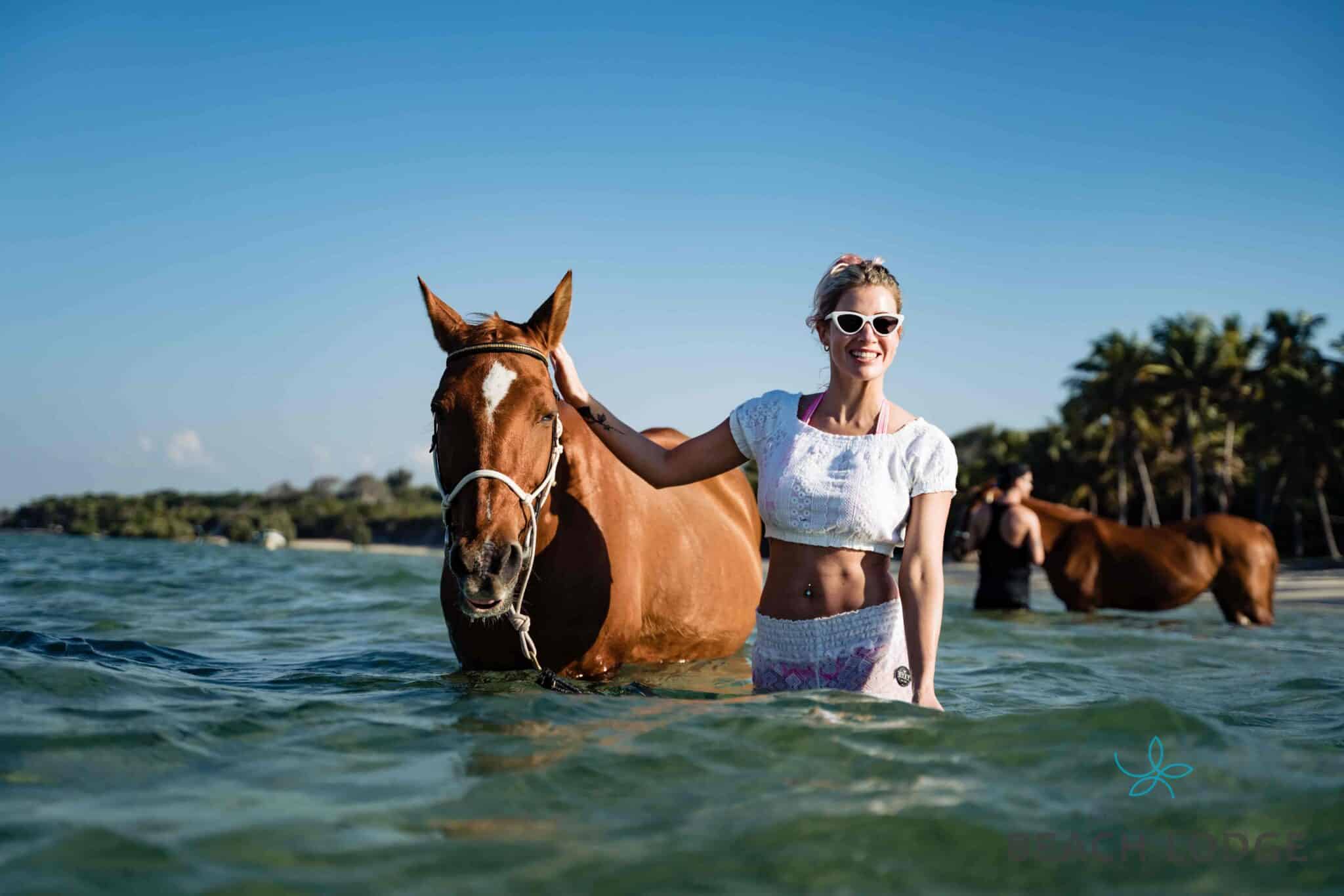 A women horse riding in the water off the beach