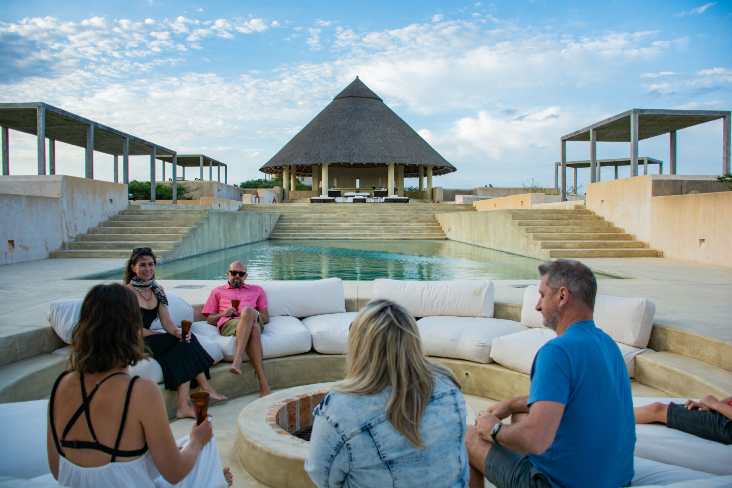 Group of people sitting around a fire pit and having some drinks