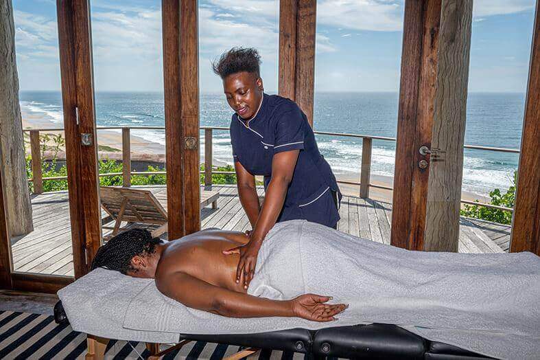 Man getting a massage at the spa in Mozambique with the ocean and beach in the distance