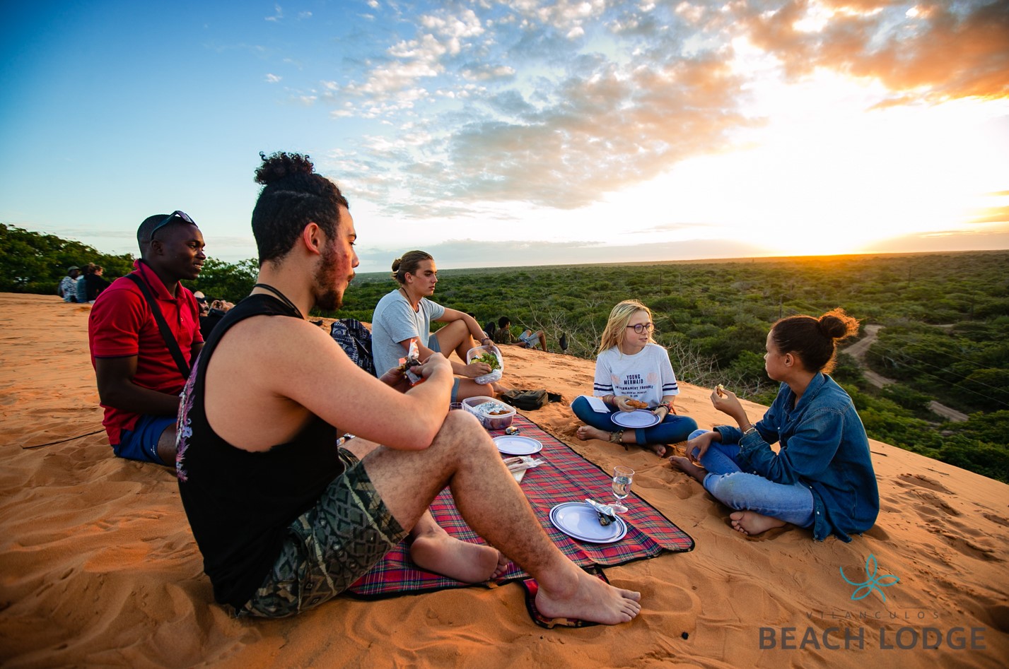 A group of friends having a picnic during sunset on the beach dunes by Vilanculos Beach Lodge